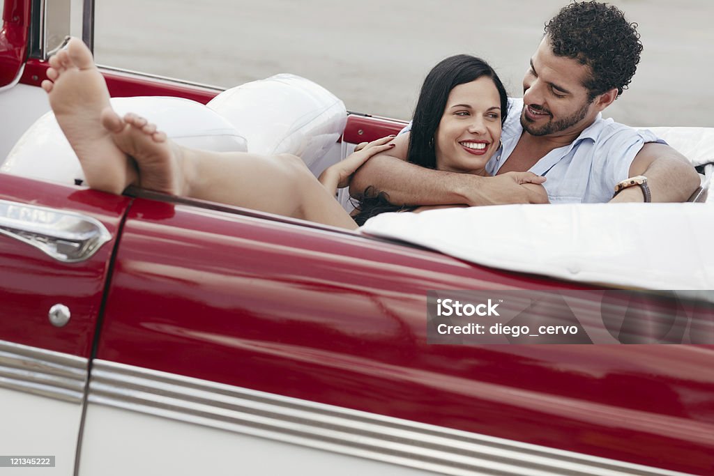 Uomo e bella donna abbracciare in cabriolet auto - Foto stock royalty-free di Abbracciare una persona