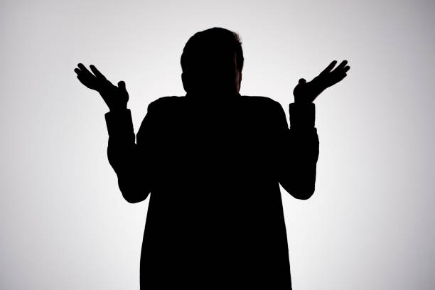 Man silhouette shrugging hands having no idea being confused stock photo