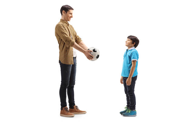 istock Young man giving a soccer ball to a boy 1213459178