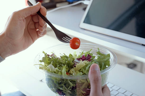 istock young man eating salad sitting at his desk 1213459513