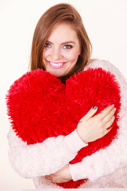 istock Happy woman holding heart shaped pillow 1213463520