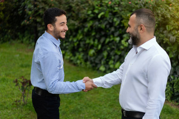 istock Two businessmen shaking hands in outdoors in front of office 1213464625