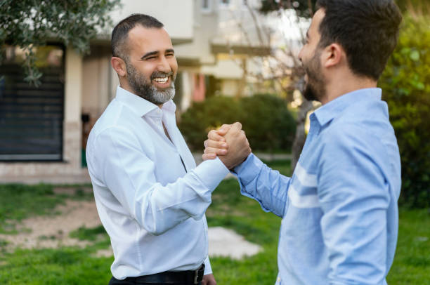 istock Two businessmen shaking hands in outdoors in front of office 1213464631