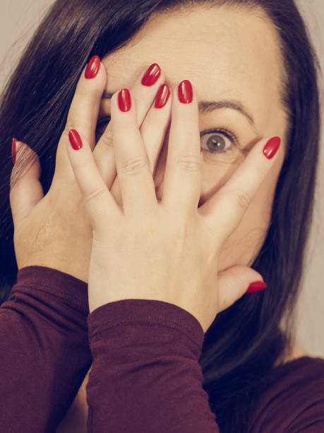 istock Woman peeking through her hands 1213464656