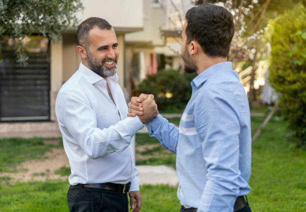 istock Two businessmen shaking hands in outdoors in front of office 1213465012