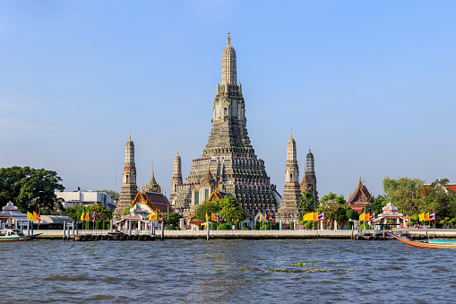 Riverbank view, looking from the Chao Praya River, of the world-famous riverside temple of Wat Arun, in Bangkok. Wat Arun has a spectacular high decorative stupa set in the heart of the temple complex as well as being in the heart of the city.