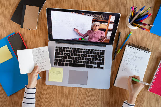 Student learning at home with online lesson High angle view of video conference with teacher on laptop at home. College student learning maths while watching online webinar, listening audio course. Top view of girl in video call with personal tutor on computer, distance and e-learning education concept. zoom classroom stock pictures, royalty-free photos & images