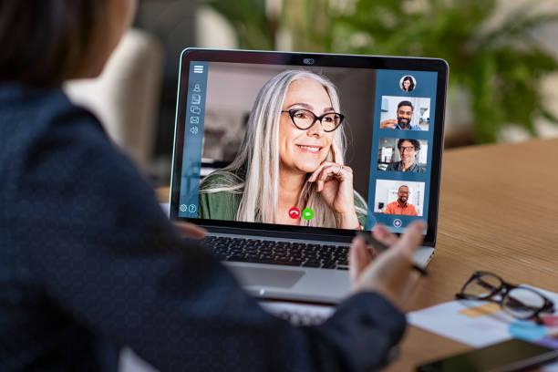 Business team in video conference Multiethnic business team having discussion in video call. Rear view of business woman in video conference with boss and his colleagues during online meeting. Senior woman making video call with partners using laptop at home: remote job interview, consultation, human resources concept. conference call stock pictures, royalty-free photos & images