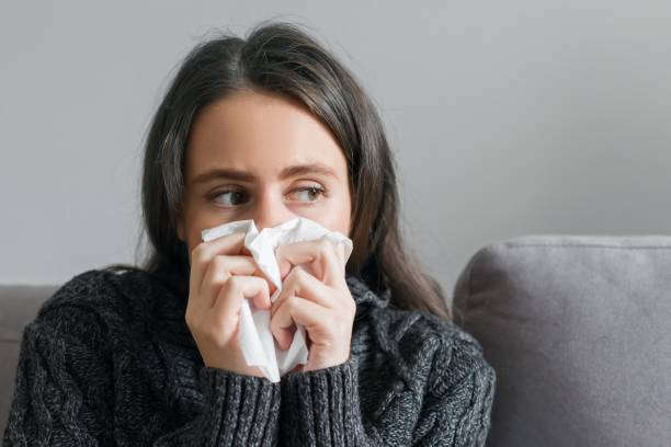 istock Sad sick young woman with handkerchief at home on sofa 1213470517