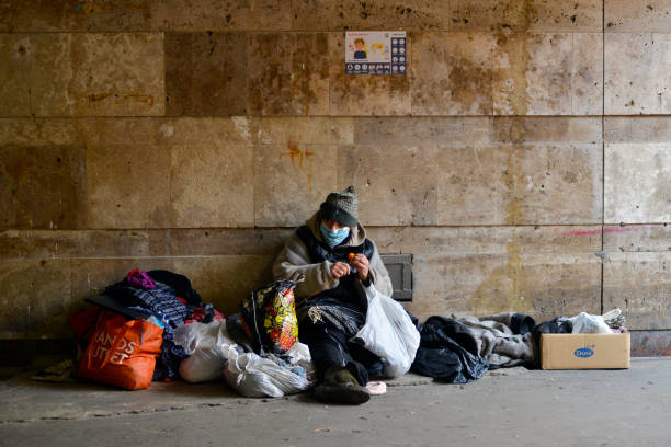 la femme sans abri dans le masque médical s’assied dans un passage souterrain près d’un métro fermé. - sdf photos et images de collection