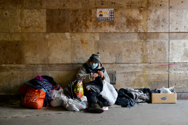 Homeless woman in medical mask sits in an underground passage near a closed subway. Kyiv, Ukraine - March 18, 2020: Homeless woman in medical mask sits in an underground passage near a closed subway. Due to the coronavirus epidemic, the Ukrainian government has closed the subway. homelessness photos stock pictures, royalty-free photos & images