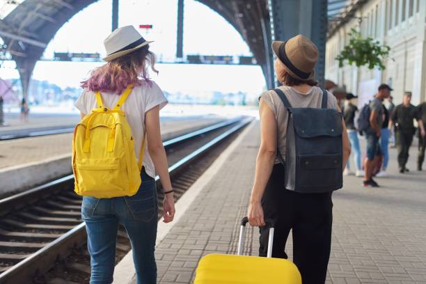 istock Two traveling women with suitcase backpacks walking along platform 1213473514