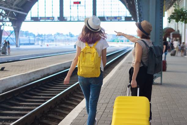 istock Two traveling women with suitcase backpacks walking along platform 1213473746