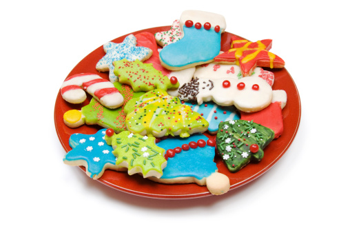 A plate of homemade iced Christmas cookies isolated on white.