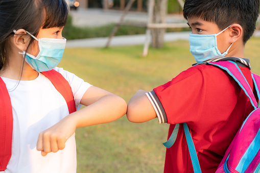La protuberancia del codo es un nuevo saludo novedoso para evitar la propagación del coronavirus. Dos niños asiáticos amigos de preescolar se reúnen en el parque escolar con las manos desnudas. En lugar de saludar con un abrazo o apretón de manos, en  photo