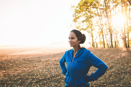 portrait of sportswoman standing in the the fields at sunrise