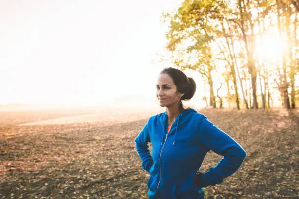 Photo of sportswoman standing on field at sunrise