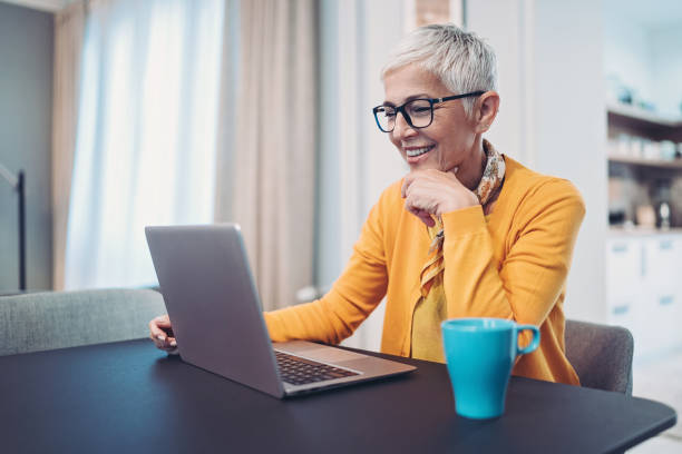 Smiling senior woman using laptop at home