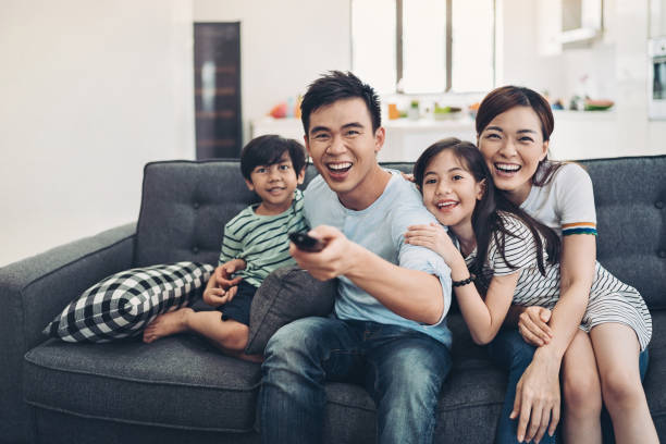 Family changing TV channels Happy family with TV remote control asian kids watching tv stock pictures, royalty-free photos & images