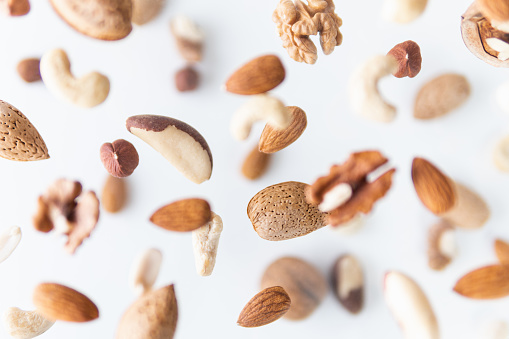 Assortment of mixed nuts flying above white background, levitation effect.