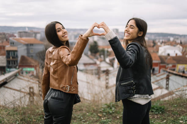 istock Twin sisters making heart shape with hands outdoors 1213493334