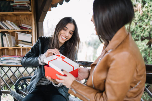 istock Smiling girl opening a gift while sitting in gazebo 1213494268