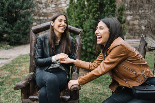 istock Sisters in wooden chairs holding hands and laughing 1213497003
