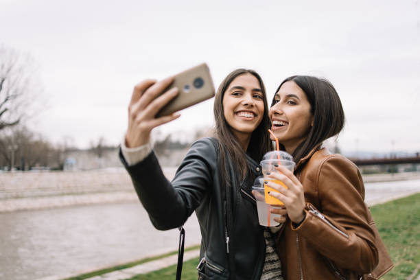 istock Smiling women with juice cups making selfie 1213498105