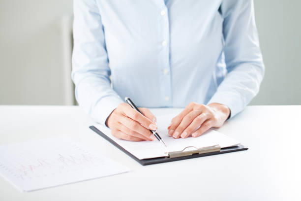 Woman's hands writing on sheet in a clipboard with a pen Woman's hands writing on sheet in a clipboard with a pen. Hands of businesswoman working with documents tabs ring binder office isolated stock pictures, royalty-free photos & images