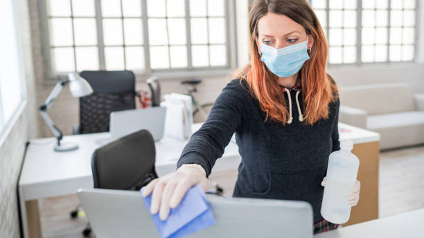 Woman in the office using disinfectant  for sanitizing monitor surface during COVID-19 pandemic Woman in the office using disinfectant  for sanitizing monitor surface during COVID-19 pandemic rubbing photos stock pictures, royalty-free photos & images