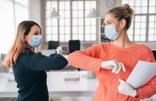 Photo of Colleagues in the office practicing alternative greeting for safety and protection during COVID-19