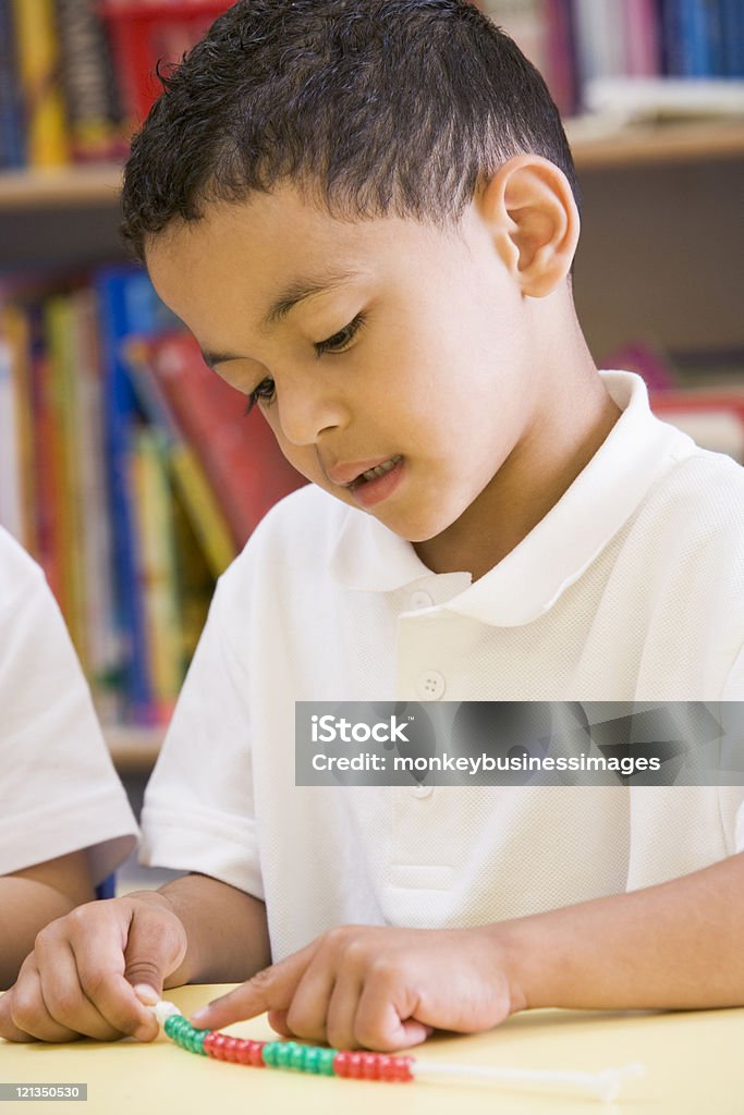 Schoolboy in a primary class Schoolboy in primary class learning maths Bead Stock Photo