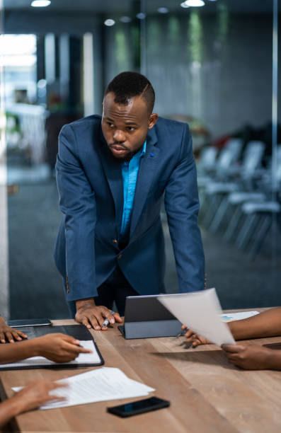 istock African businessman talking with a diverse group colleagues while having a meeting together around a table in an office boardroom 1213505402