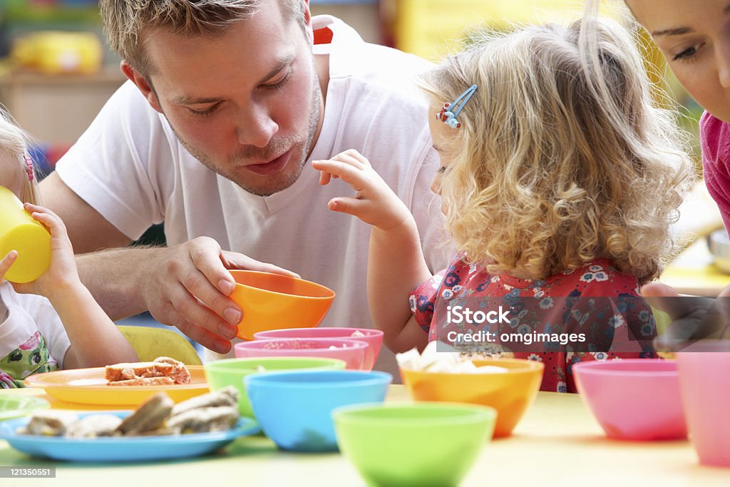 Man playing with children using colorful cups Man with children playing together in nursery school Preschool Building Stock Photo
