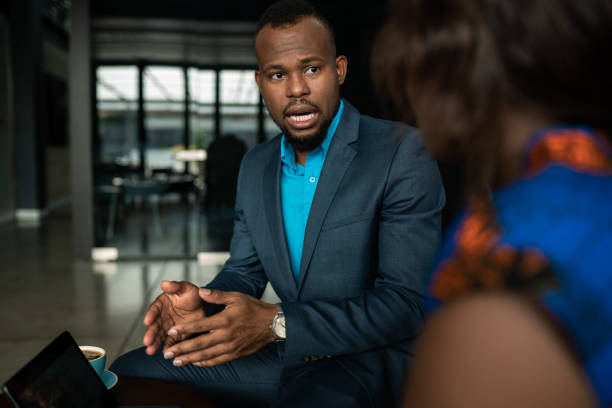 Multiracial professionals with an international perspective convening in a business meeting. Actively discussing ideas and making business decisions in a corporate environment, they wear formal business attire.