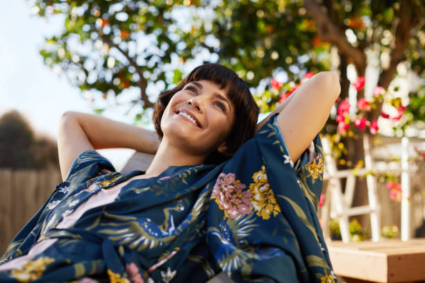 istock Smiling woman lying back outside on a patio deck chair 1213506274