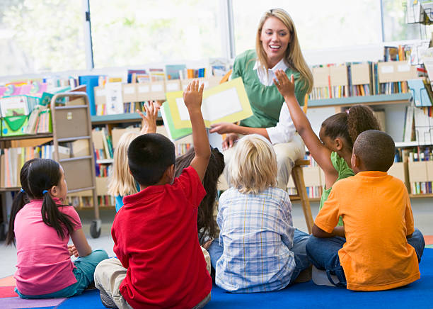 Kindergarten teacher reading to children Kindergarten teacher reading to children in library preschool teacher stock pictures, royalty-free photos & images