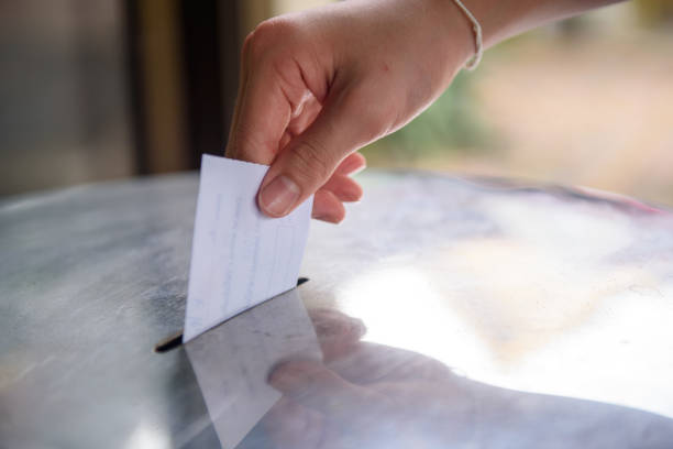 Man hand inserting vote into ballot box