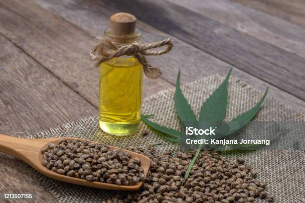 Hemp Oil In A Glass Bottle Tied With A Bow Hemp Seeds In A Wooden Spoon On The Table The Concept Of Bringing Hemp Oil Extracted As A Medicine By Natural Methods Doctors And Marijuana Stock Photo - Download Image Now