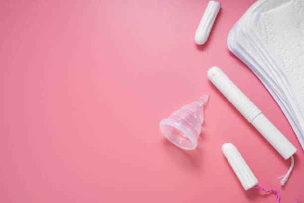 Woman hygiene products, menstruation, cotton tampons, sanitary pads, menstrual cup for woman critical days. Pink background with copy space. Woman hygiene products, menstruation, cotton tampons, sanitary pads, menstrual cup for woman critical days. Pink background with copy space for text. menses stock pictures, royalty-free photos & images