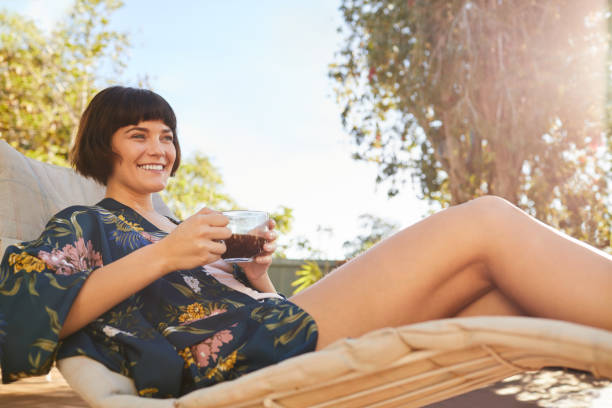 istock Smiling woman in a robe drinking tea on a deck chair outside 1213511735