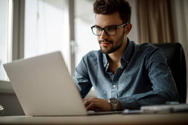 jonge zakenman die aan laptop werkt - male employee office stockfoto's en -beelden