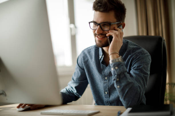istock Young smiling man using mobile phone in home office 1213513719