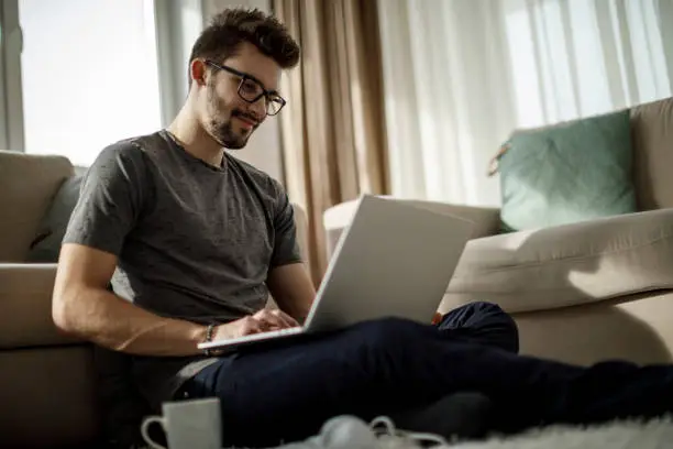 Photo of Young man studying and working on laptop at home