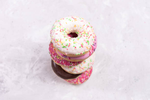 Top view to stack of six doughnuts with multicolored glaze on center of blurred concrete background. Selective focus.