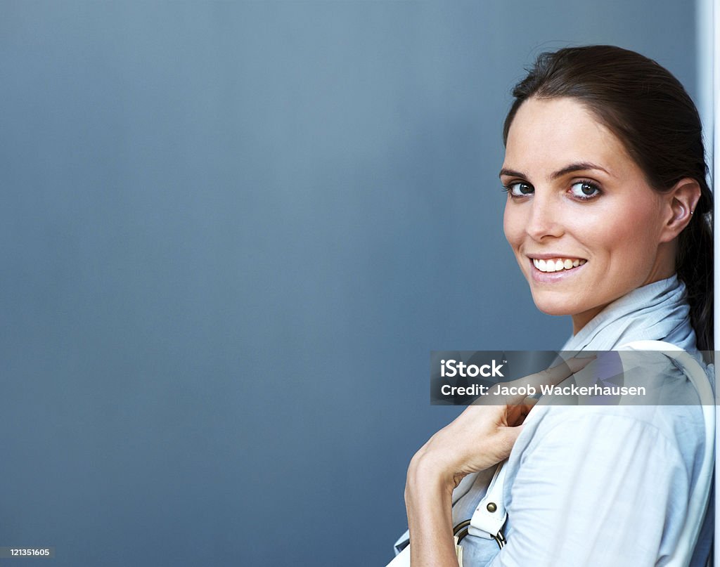 Jolie jeune femme souriant sur fond gris - Photo de A la mode libre de droits