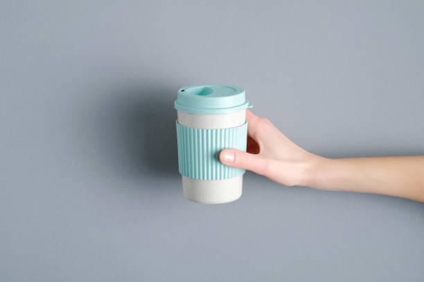 istock Eco-friendly takeaway bamboo coffee cup in female hand. Top view 1213520007
