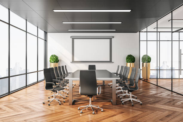 istock Empty screen for projector on wall in clean conference room. 1213520374
