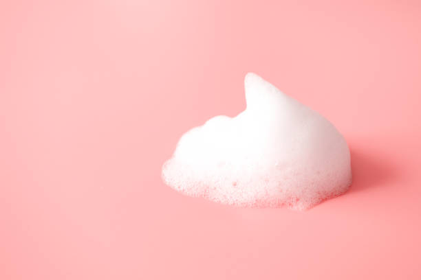 istock White foam snear from soap, shampoo or cleanser on pink background with selective focus. Close-up, macro 1213524924