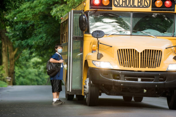istock school boy with surgical mask at bus stop. 1213525118